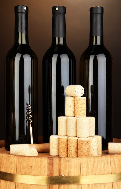 Wine and corks on barrel on brown background