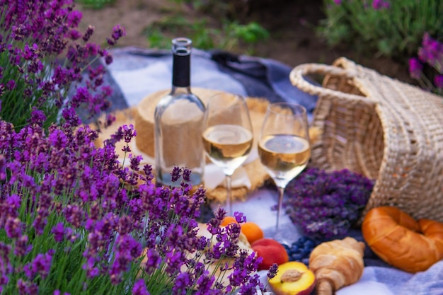 Wine fruits berries cheese glasses picnic in lavender field Selective focus