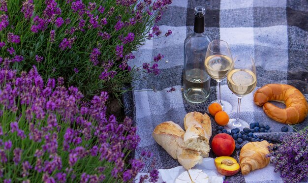 Wine fruits berries cheese glasses picnic in lavender field Selective focus