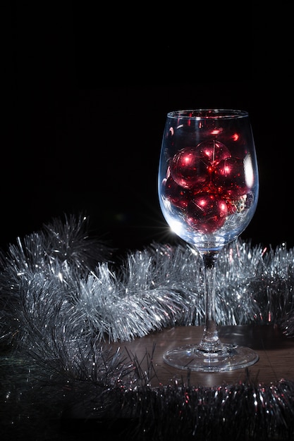 Wine glass filled with Christmas balls. On a black background.