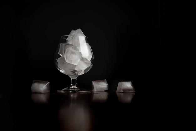 Wine glass filled with ice cubes in soft lighting on dark background