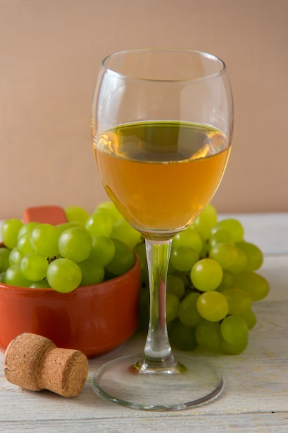 Wine glass, green grapes on plate on table.