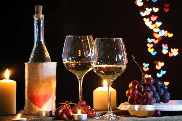 Wine glass near bottle on hearts bokeh background