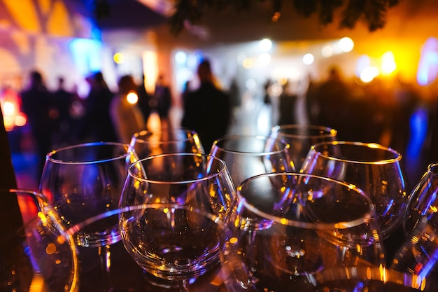 Wine glasses in the glare of light on blurred silhouettes of people background