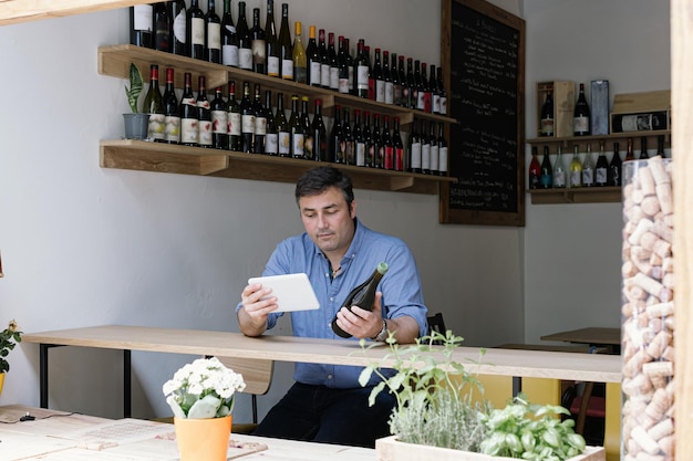 Wine store manager checking the data's of wine using tablet online business