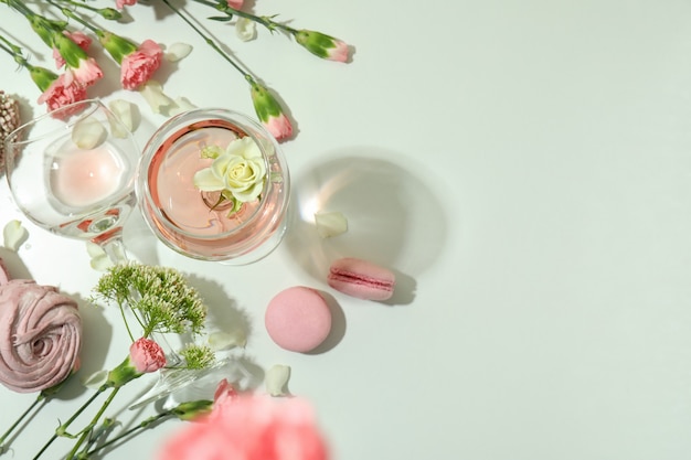 Wine, sweet food and flowers on white table