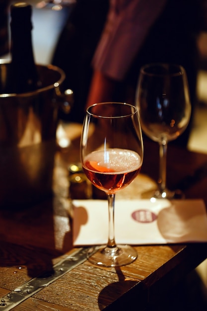 Wine tasting. On the wooden table is a glass filled with pink champagne, a bucket for cooling bottles