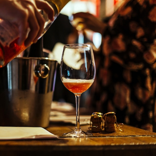 Wine tasting: on a wooden table there is a glass with pink champagne.