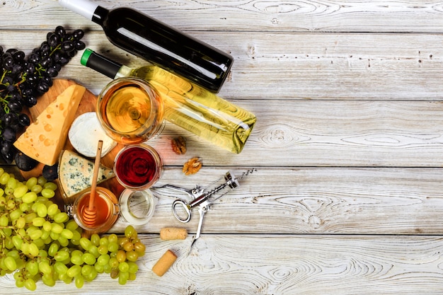 Wine with branches of white grapes. On a wooden table.