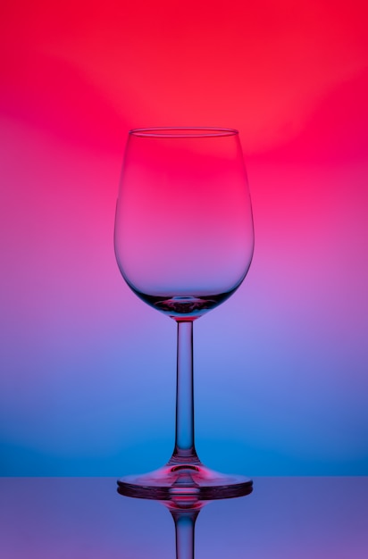 Wineglass on a high and thin stalk on a colored background