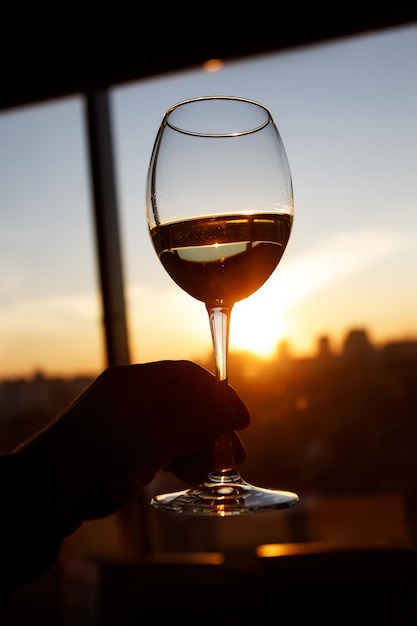 Wineglass over sunset Window and city on the background