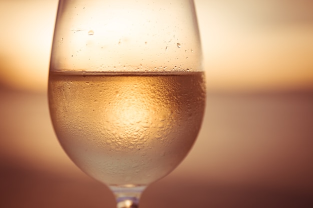 Wineglass of white wine at sunset with dramatic sky