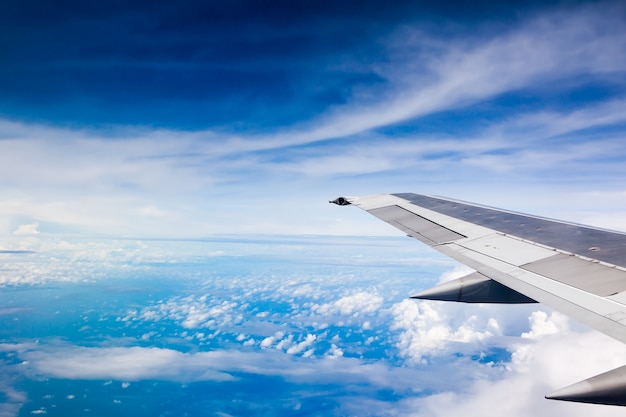 Wing of an airplane flying above inshore in the blue sky and cloud.