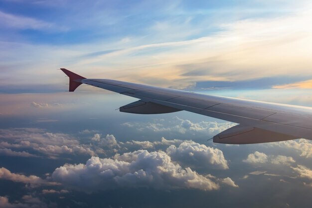 Wing of an airplane flying above the sunset clouds Looks at the sky from the window of the plane air travel