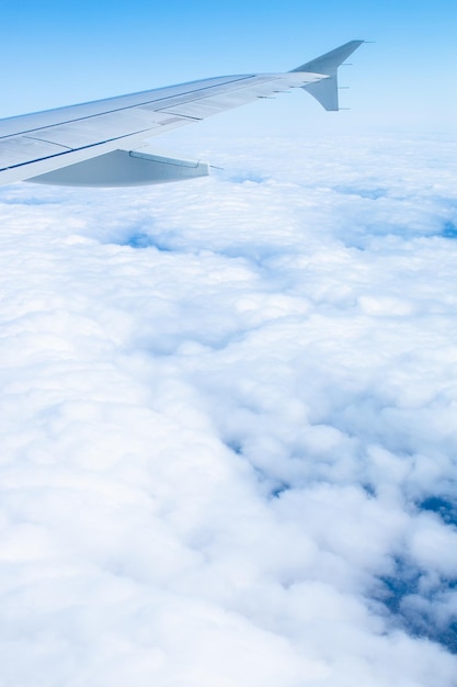 Wing of an airplane flying over white clouds and blue sky