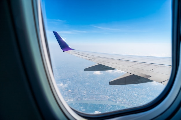 The wings of the plane on the background of blue sky and clouds beautiful