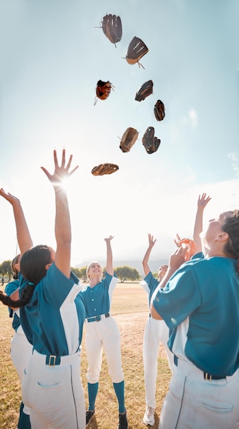 Winning team baseball and celebration with women group throwing their gloves in victory and feeling happy after a game or match Teamwork softball and success of girls players enjoying a sport