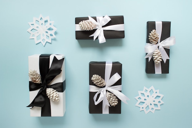 Winter arrangement of presents with pine cones, paper handmade snowflakes and satin bows 