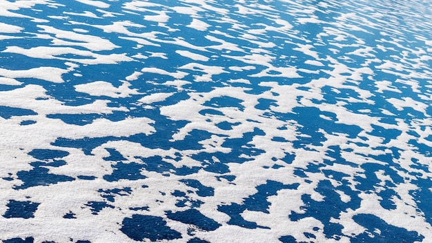 Winter background with blue ice of the river covered with white snow