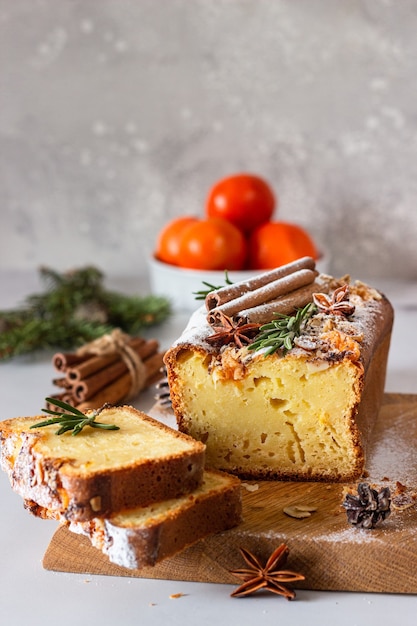 Winter bakery. Citrus loaf moist cake decorated with tangerines, rosemary, spices and sugar powder.