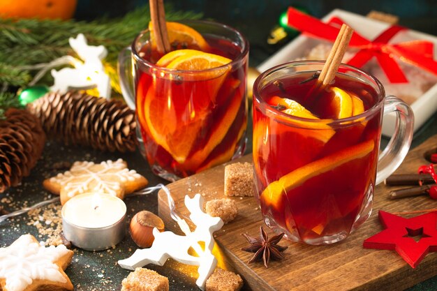 Winter Christmas mulled wine close-up with orange and spices on the festive table.