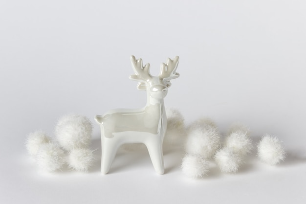 Winter composition with white glossy porcelain raindeer with white fluffy balls