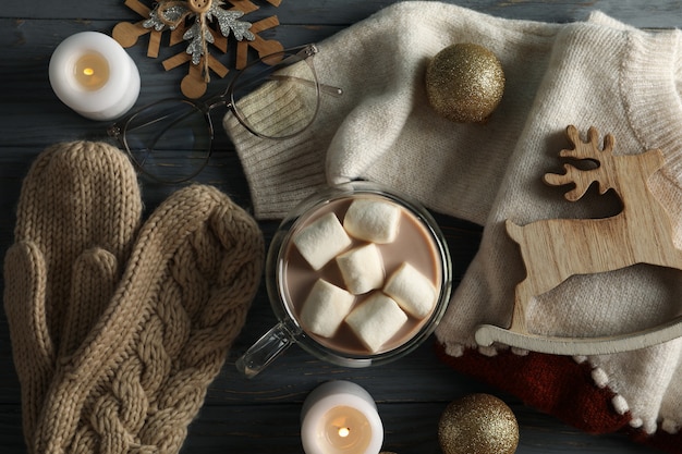 Winter concept with coffee with marshmallow, sweater and candles on wooden background