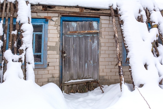 Winter countryside landscape, dilapidated abandoned ruined building covered in snow.