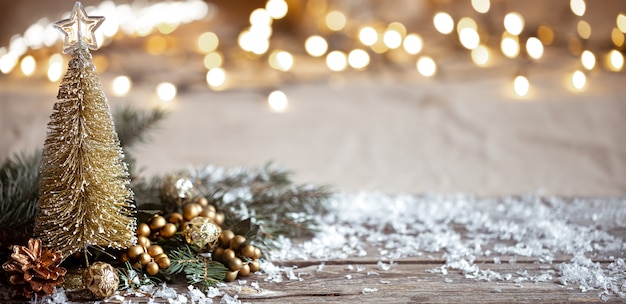 Winter cozy background with festive decor details, snow on a wooden table and bokeh. concept of a festive atmosphere at home.