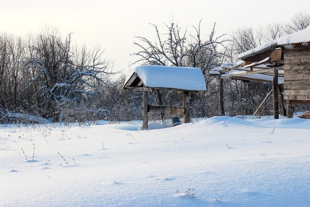 Winter fairy tale in the village with snow-covered roofs, wells