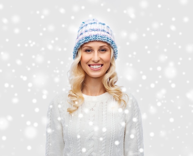 winter, fashion, christmas and people concept - smiling young woman in winter hat, sweater and gloves