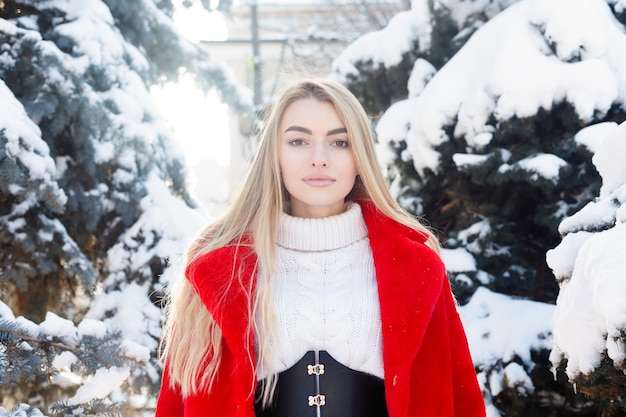 Winter, fashion, people concept - fashion Portrait of a beautiful young woman walks around the city smiling red fur coat close-up snowflakes cold winter, breathe fresh air at frost winter day. sunset