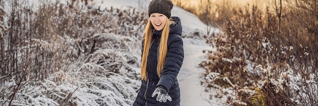 Winter girl throwing snowball at camera smiling happy having fun outdoors on snowing winter day