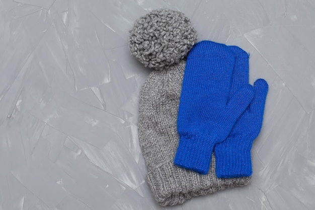 A winter hat and mittens tied together lie on a gray background View from above Woolen things winter clothes