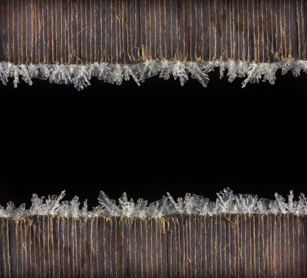 Winter holiday Christmas new year background frame of macro photo frost on old wooden planks with black space for text