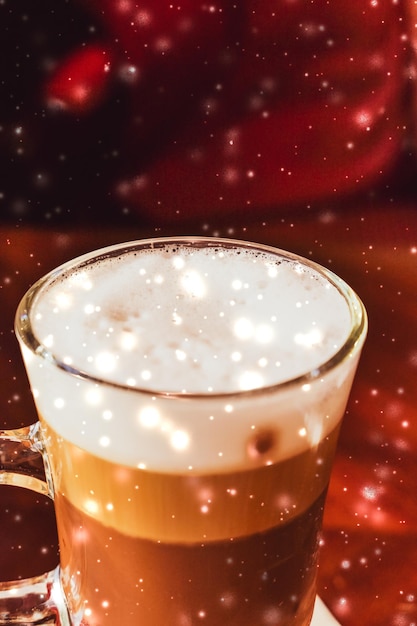 Winter holiday latte coffee glass and glowing snow in a restaurant Christmas time menu recipe