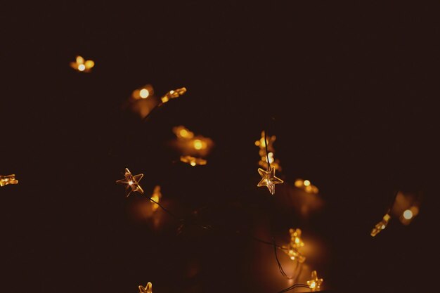 Winter holiday lights against dark brown Bright New Year garland shaped like stars brightly illumin