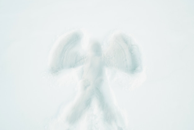 Winter holidays and christmas concept. Angel silhouette on snow surface top view.