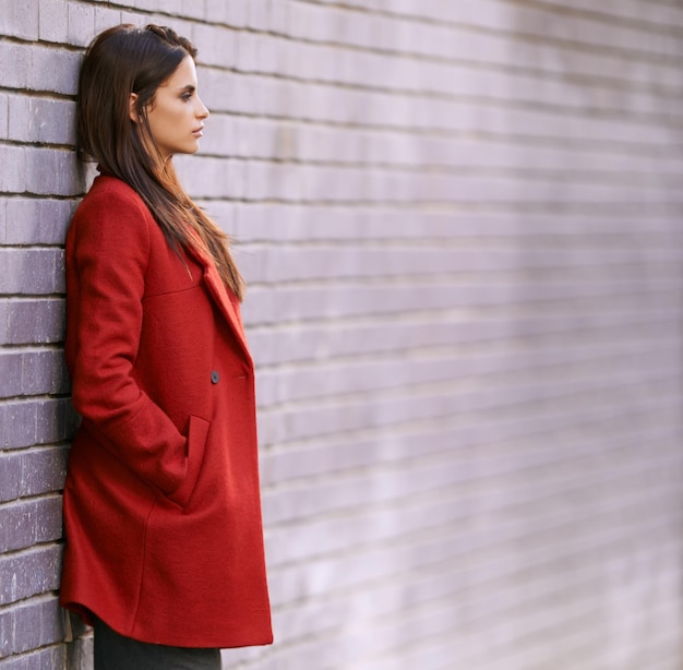 Photo winter jacket and woman on wall with fashion in city for travel with cool style in red coat streetwear clothes and girl outdoor on building background with confidence and pride in new york spring