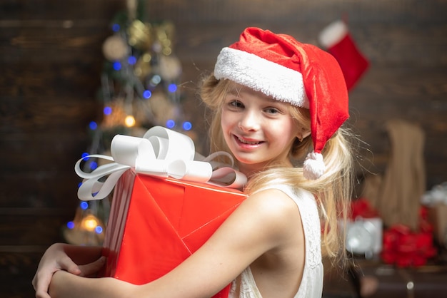 Winter kids Portrait of happy Little girl looking at decorative toy ball by Christmas tree Joyful te