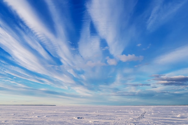 Winter landscape over frozen river with blue bright sky and white clouds