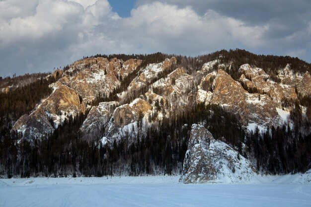 Winter landscape gloomy mountains covered with forest under a cloudy sky Climate weather