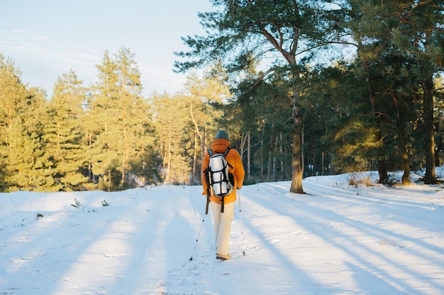 Winter landscape a man with a backpack and warm winter clothes in the forest traveling in the mountains