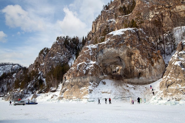 Winter landscape mountains and rocks covered with forest on the bank of a frozen river