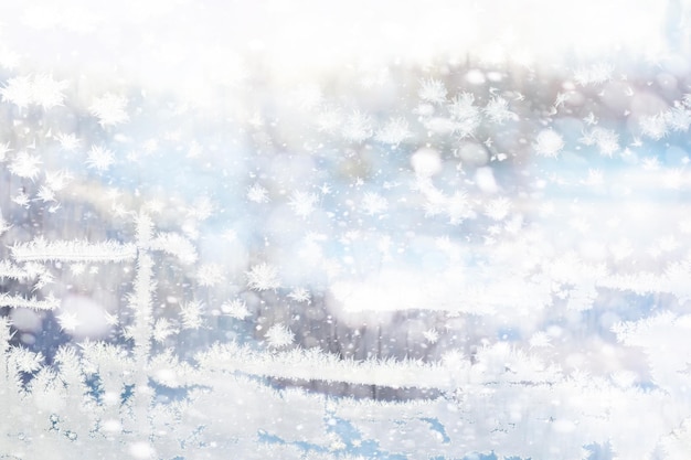 Winter landscape through a frozen window Blurred snow background Trees and plants covered with snow