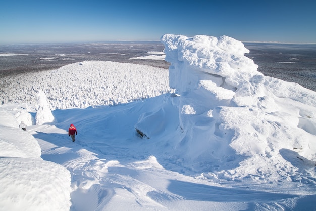 Winter landscape. A tourist climbs on top of a mountain range in winter cold clear weather