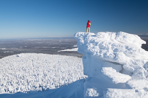 Winter landscape. A tourist stands on the top of a mountain range in winter cold clear weather