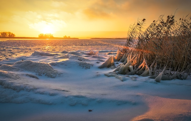 Winter landscape with frozen lake and sunset fiery sky. Composition of nature.