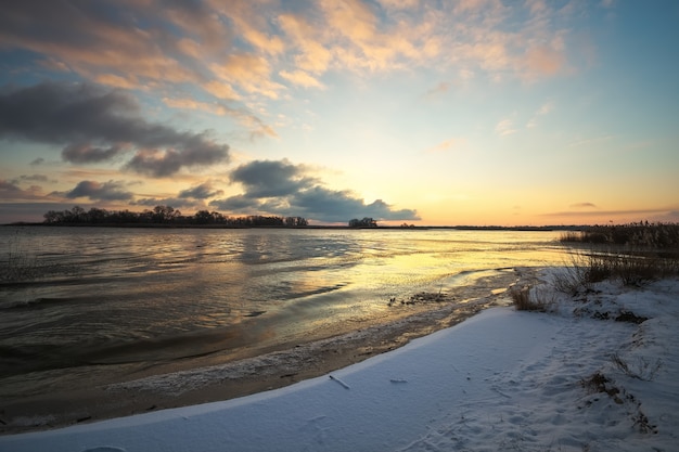 Winter landscape with frozen lake and sunset sky. Colorful orange sky