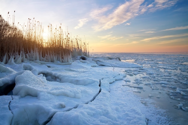 Winter landscape with frozen lake and sunset sky. Composition of nature.